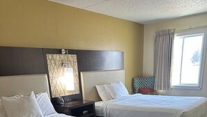 Una habitación de hotel con dos camas, una mesita de noche, una lámpara y una ventana con cortinas.