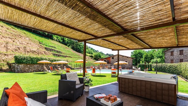 Ein Außenbereich mit Terrasse, Korbmöbeln, einer Bar und Sonnenschirmen.