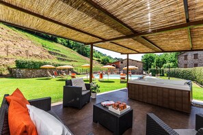 An outdoor patio area with wicker furniture, a bar, and umbrellas. - Family sized apartment with external patio, barbecue and swimmingpool (Toscana)