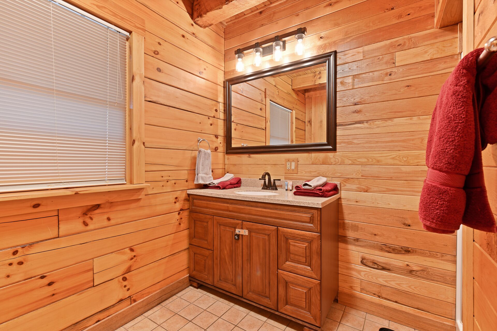 A wooden cabin bathroom with a sink, mirror, and towel rack.