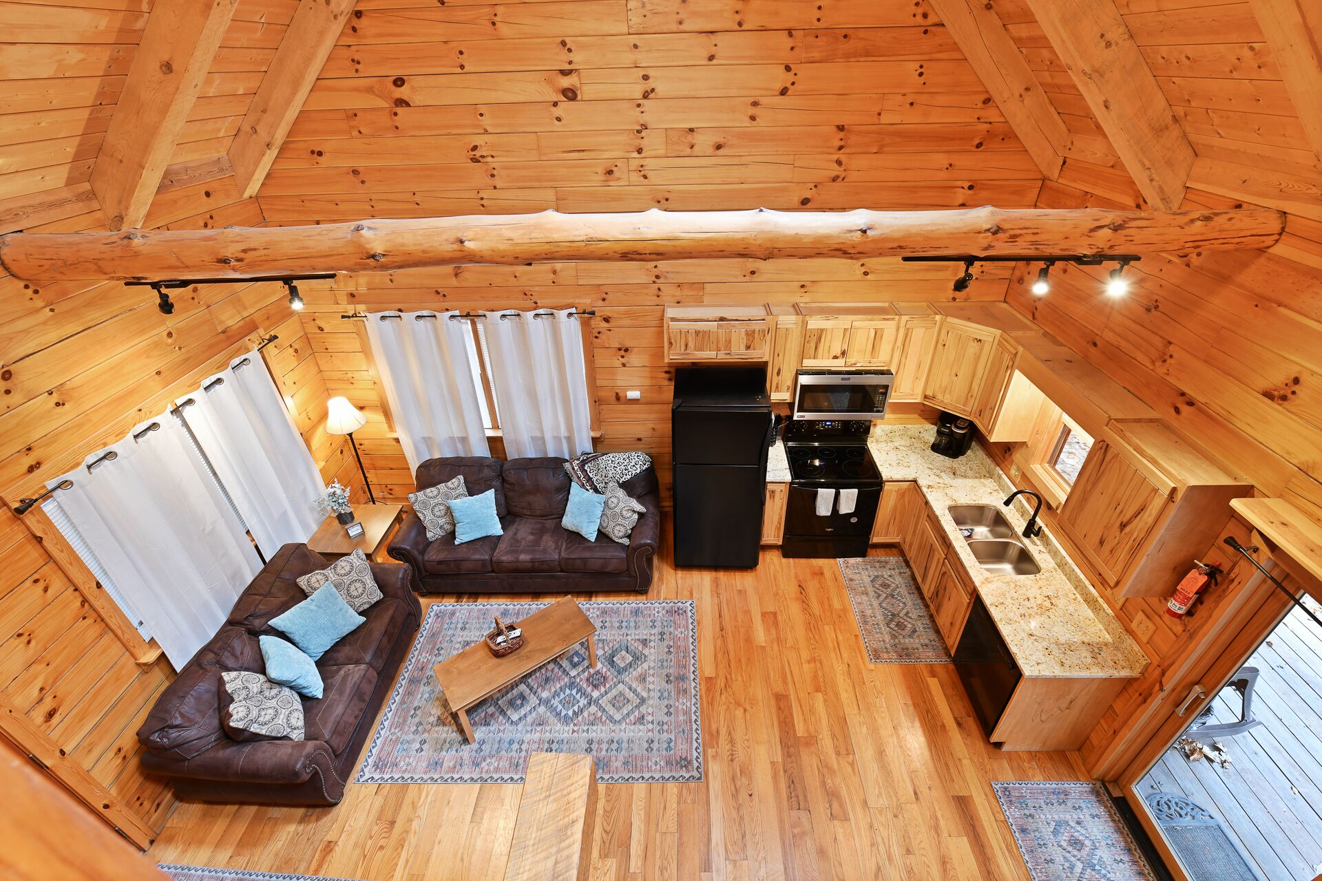 A cozy cabin interior with a living area, kitchenette, and wooden walls.