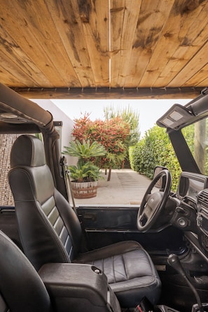 Interior de vehículo con volante, tablero de control y dos asientos de cuero negro.