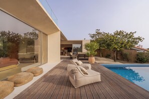 Una terraza moderna al aire libre con piscina, sillas de descanso y zona de comedor.