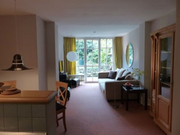 Una habitación con una mesa de comedor, un sofá y una ventana con cortinas.