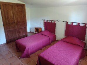 A room with two single beds, a wooden wardrobe, and a small bedside table. - 🌿 Gîte "Le Noyer" - Le Mas des Charrettes (Provence-Alpes)