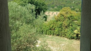 A view through a doorway of a landscape with a hill, trees, and a clear sky. - 🌿 Gîte "Le Noyer" - Le Mas des Charrettes (Provence-Alpes)
