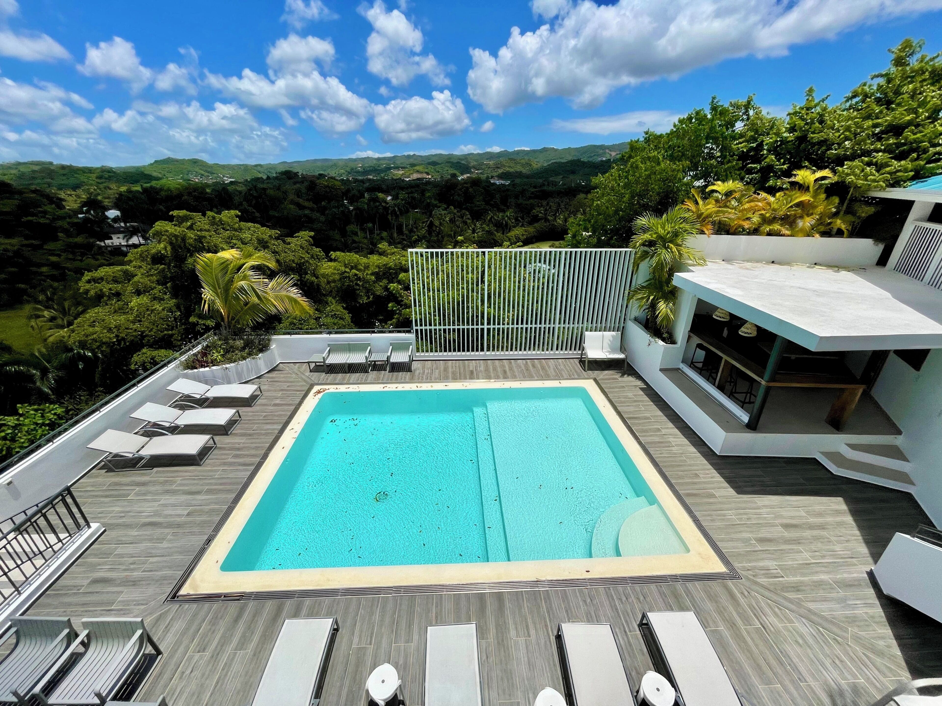 Ein Pool auf dem Dach mit Liegestühlen und Blick auf die umliegende Landschaft sowie ein modernes Gebäudegerüst.