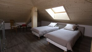 Een kamer met twee bedden, een dakraam, een stoel en een bureau.