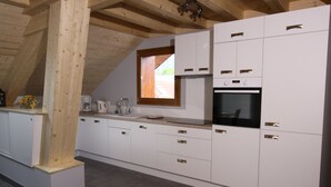 Een moderne keuken met witte kastjes, een inbouwoven en een raam boven de gootsteen.
