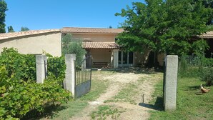 A house with a tiled roof, a fenced yard, and a chicken.