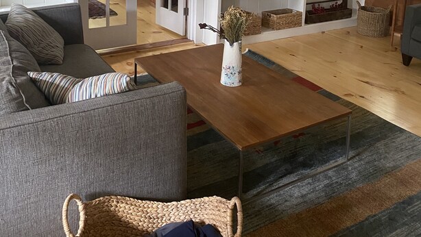 A living room with a sofa, coffee table, TV, and shelves with decorative items.