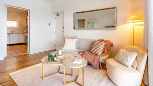Una sala de estar moderna con un sofá, dos mesas auxiliares y un espejo grande.