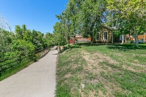 A paved path leading to a building with a brick facade, surrounded by greenery and trees. - The Vintage Golden Gem – Near Clear Creek (Golden)