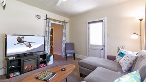 A living room with a television, a sofa, a coffee table, and a ceiling fan.