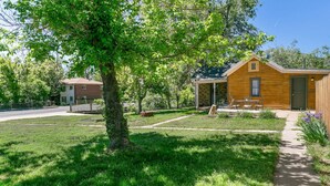 A wooden cabin with a covered porch, surrounded by a well-maintained lawn and trees.