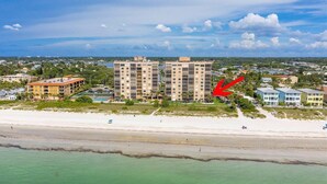 Un hotel frente al mar con varias construcciones, una playa y cielos despejados.