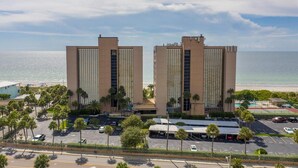 Un hotel frente a la playa con dos edificios altos, un estacionamiento y una zona de piscina.