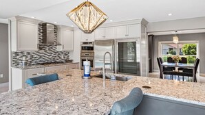 A modern kitchen with a central island, stainless steel appliances, and a decorative chandelier.