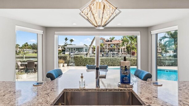A kitchen with a large window, a chandelier, and a pool view.