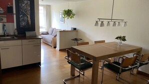 A modern kitchen with a dining area, wooden flooring, and a hanging plant. - Apartment AltstadtErleben 2 (upper floor) (Naumburg (Saale))