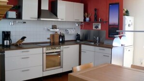 A modern kitchen with white cabinets, a wooden countertop, and a built-in oven. - Apartment AltstadtErleben 2 (upper floor) (Naumburg (Saale))
