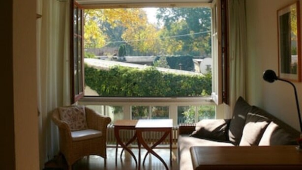 A room with a large window, a sofa, a chair, and a table. - Apartment AltstadtErleben 2 (upper floor) (Naumburg (Saale))