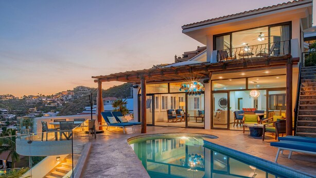 A modern house with a pool, outdoor seating, and a view of the city.