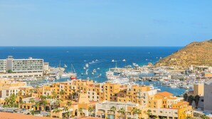 A coastal town with a marina filled with boats, surrounded by multi-story buildings with balconies.