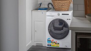 A laundry room with a washing machine, a sink, and a skylight above.