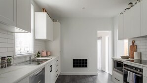 A modern kitchen with white cabinetry, a stainless steel dishwasher, and a built-in oven.