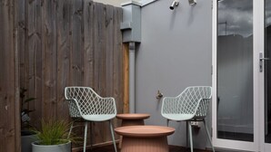 A patio area with two white wireframe chairs and a round table.