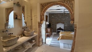 A bathroom with two stone sinks, a mirror, and a stone fireplace.