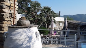 A stone wall, a large white urn, a pool, and a lounge area with umbrellas.