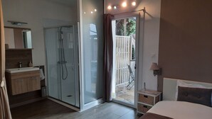 Een moderne slaapkamer met een glazen douche, een houten wastafel en uitzicht op de omgeving.