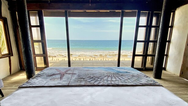 A room with a large bed, a starfish decoration, and a view of the beach.