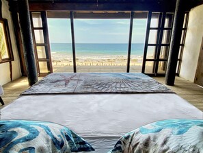 Quarto com cama grande, decoração em formato de estrela-do-mar e vista para a praia.