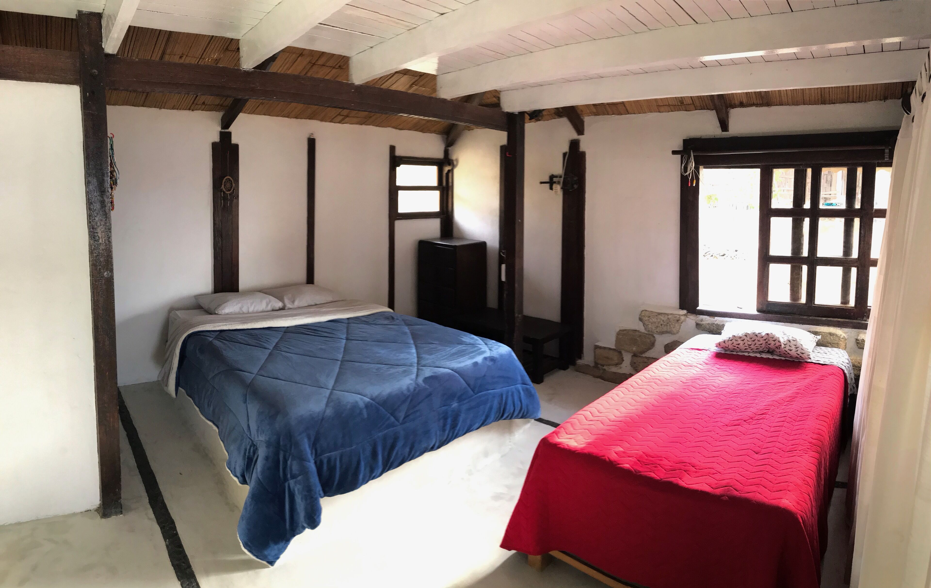 Een slaapkamer met een bed, een dressoir en een raam.