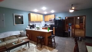 A compact living space with a kitchenette, a sofa, a dining table, and a small kitchen island.