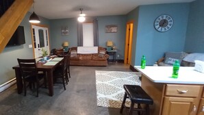A cozy living room with a dining area, a staircase, and a kitchen.
