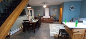 Un salon chaleureux comprenant un coin repas, un escalier et une cuisine.