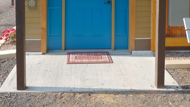 A blue door with a glass panel and a welcome mat.