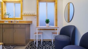 Una cocina compacta con ventana, un lavamanos, una encimera y una mesa pequeña con dos taburetes.
