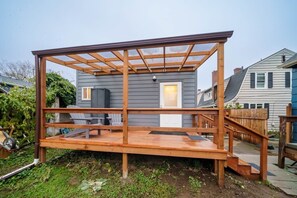 Eine Holzterrasse mit einer Pergola, einer Tür und einem Fenster.