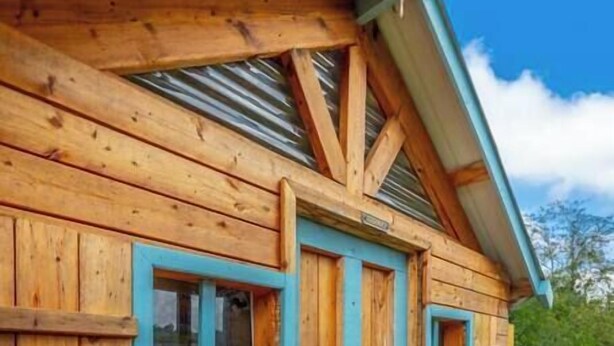 A wooden cabin with a porch, a door, and two windows with blue trim. - Suite 112: Comfort at Rock Spring Resort (Rock Spring)