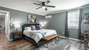 A bedroom with a bed, bedside lamps, a ceiling fan, a rug, and a window with blinds. - Suite 112: Comfort at Rock Spring Resort (Rock Spring)