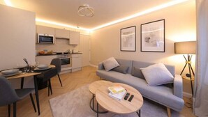 Un appartement moderne comprenant un coin repas, un canapé, une table basse et une cuisine en arrière-plan.