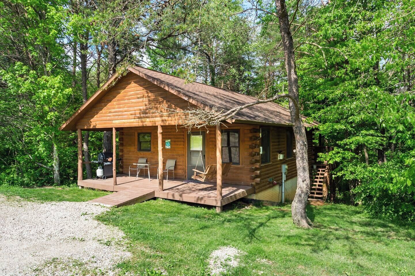 A wooden cabin with a porch, a small deck, and a ladder leading to the entrance.