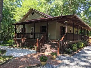 Surrounded by a serene garden, this cabin features a covered porch and a staircase leading to a cozy retreat.