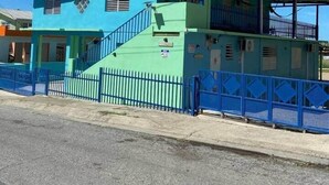 A two-story building with a green roof and a blue fence. - Cayo Enrique at Guayacán Guest House (Lajas)