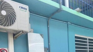 An air conditioning unit, a no parking sign, and two electrical boxes on a building's exterior wall. - Cayo Enrique at Guayacán Guest House (Lajas)